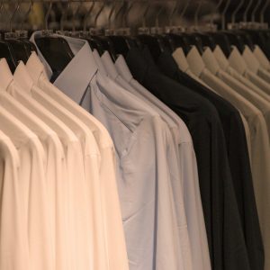 Shirts of various colors hang on hangers.